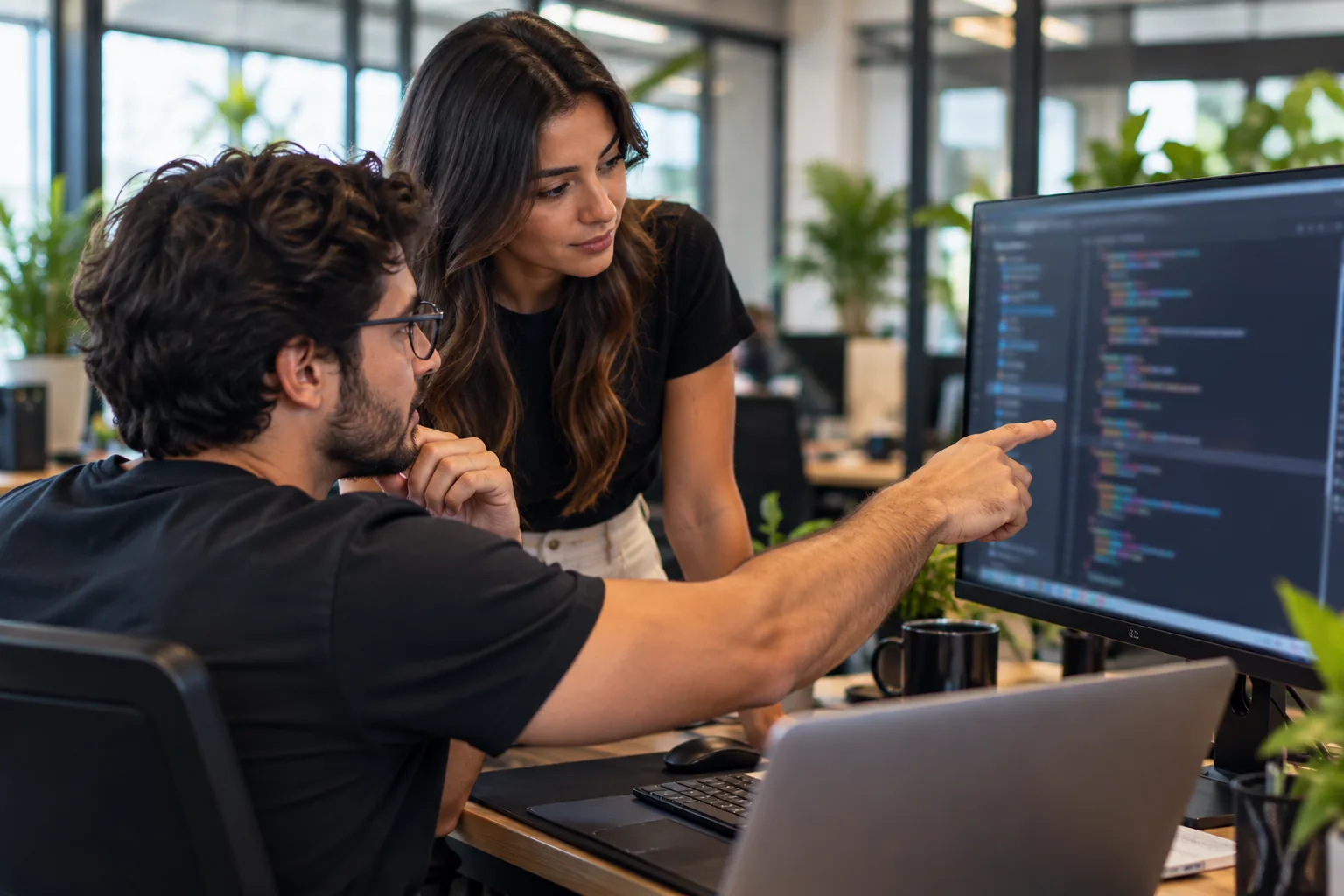 Duas pessoas de tecnologia diante de um monitor com código, conversando sobre a integração.